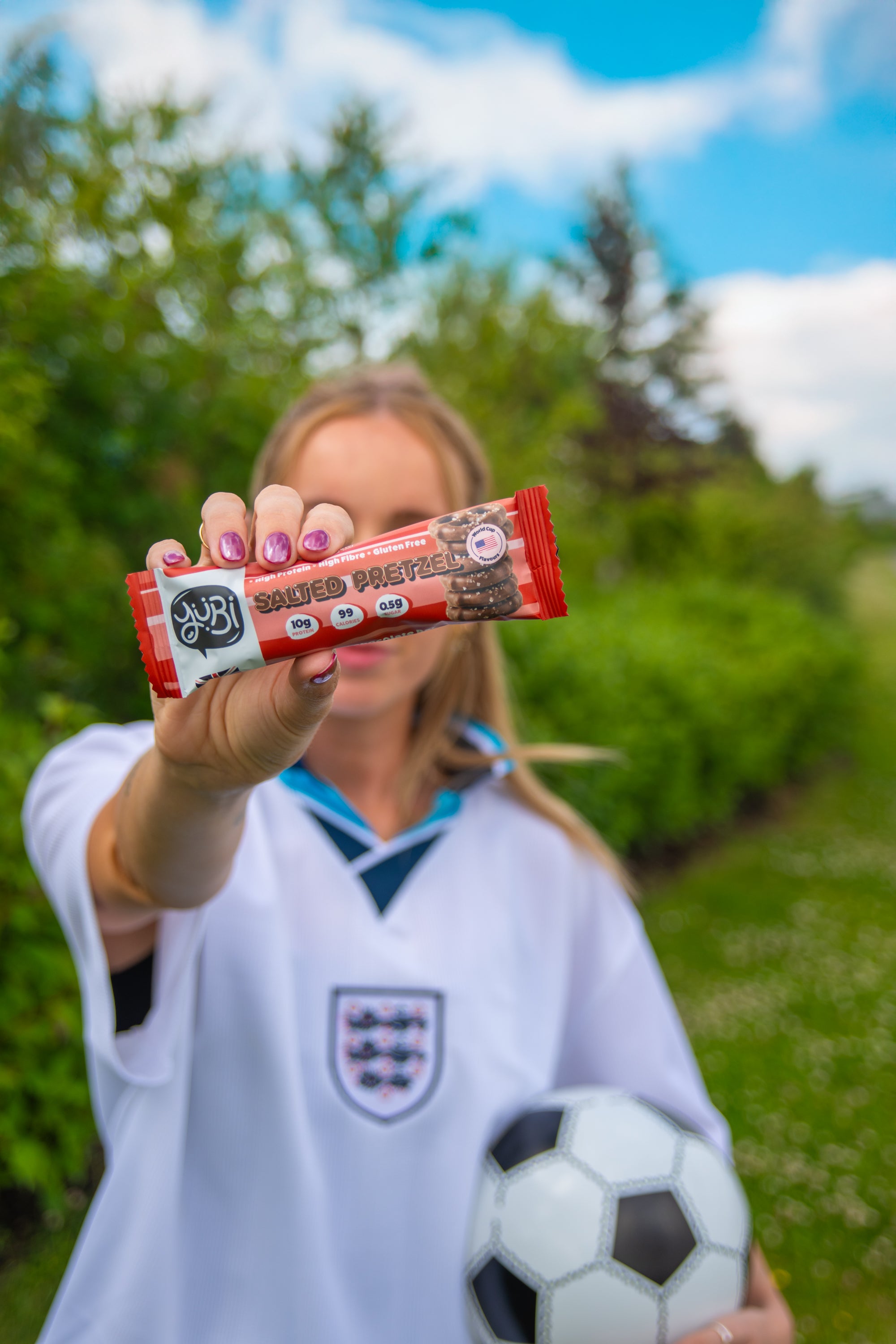 YuBi summer of soccer protein bars vegan gluten free low sugar salted pretzel with woman in england football shirt