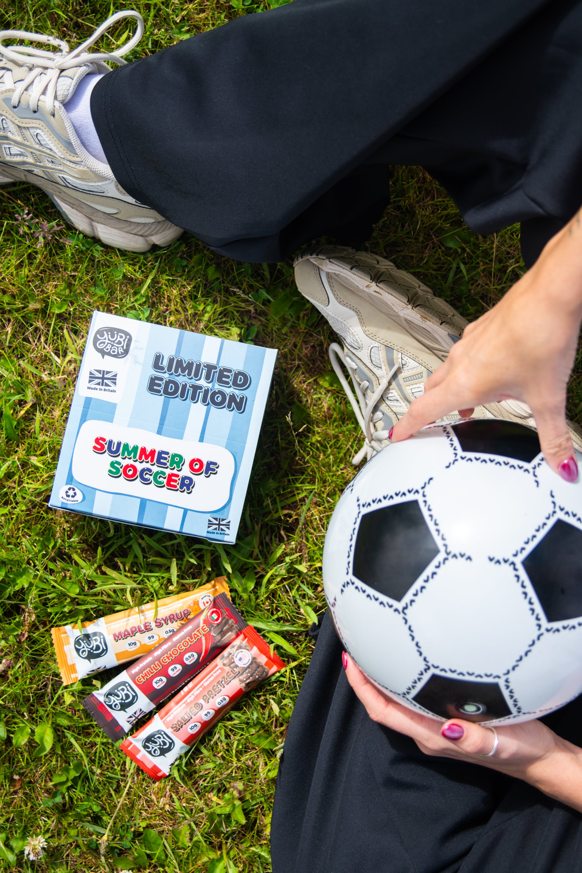 YuBi summer protein bars with football and cilli chocolate slted pretzel maple syrup on a football pitch